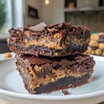 ['Close-up of decadent Peanut Butter Cup Brownies with a rich, gooey texture.', 'Side view of moist brownies topped with melted chocolate and peanut butter cups.', 'Layered brownies showcasing a creamy peanut butter swirl and dark chocolate chunks.', 'Delicious brownie slice revealing a soft interior and crunchy peanut butter topping.']