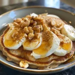 ['A side view of a colorful protein pancake bowl topped with fresh fruit and drizzled with syrup.', 'Close-up of a protein pancake bowl featuring fluffy pancakes, yogurt, and vibrant toppings.', 'A delicious protein pancake bowl adorned with berries, nuts, and a touch of maple syrup.', 'A detailed view of a protein pancake bowl with stacked pancakes and assorted toppings.']
