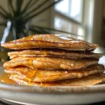 ['Close-up view of golden brown protein pancakes stacked on a plate.', 'Side view of fluffy protein pancakes drizzled with syrup and topped with berries.', 'Juicy protein pancakes presented on a white plate, showcasing ingredients.', 'Detailed shot of protein pancakes, highlighting their texture and color.']