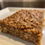 ['Close-up view of a moist pumpkin spice protein bar with chocolate chips.', 'Side view of a gluten-free pumpkin spice protein bar showcasing its texture.', 'Juicy pumpkin spice protein bars arranged attractively on a white surface.', 'Deliciously drizzled pumpkin spice protein bar highlighting its ingredients.']