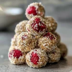 ['Close-up image of Berry Cashew Protein Bites on a white plate.', 'Side view of Berry Cashew Protein Bites showcasing their juicy texture.', 'Detailed shot of Berry Cashew Protein Bites featuring vibrant raspberries.', 'Close view of an assortment of Berry Cashew Protein Bites with a coconut base.']