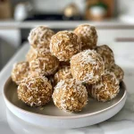 ['Close-up view of golden Vanilla Coconut Balls on a textured surface.', 'Side view of delicious Vanilla Coconut Balls sprinkled with coconut flakes.', 'Juicy Vanilla Coconut Balls arranged on a plate, showcasing their texture.', 'Brightly lit photo of Vanilla Coconut Balls with a few chocolate chips visible.']