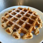 ['Close-up view of golden, fluffy apple cinnamon waffles topped with fresh apple slices.', 'Side profile of a stack of eggless apple cinnamon waffles dusted with powdered sugar.', 'Detailed image showcasing warm apple cinnamon waffles with a crispy exterior and soft interior.', 'Juicy apple cinnamon waffles served with a drizzle of syrup and sprinkled cinnamon.']