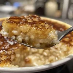 ['Creamy caramel rice pudding in a bowl with a spoon beside it.', 'Close-up view of rich caramel rice pudding, garnished and ready to serve.', 'Luxurious caramel rice pudding with a glossy finish, captured in natural light.', 'Bowl of warm caramel rice pudding showcasing its smooth texture and caramel sheen.']