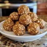 ['A close-up side view of Cinnamon Roll Energy Bites on a white plate.', 'Juicy and delicious Cinnamon Roll Energy Bites arranged attractively on a wooden surface.', 'A detailed view of homemade Cinnamon Roll Energy Bites, showcasing their texture and color.', 'An iPhone photo capturing the rich appearance of Cinnamon Roll Energy Bites with drizzled maple syrup.']