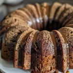 ['Close-up side view of a moist gingerbread Bundt cake topped with a glossy glaze.', 'Delicious gingerbread Bundt cake displaying rich brown color and decorative pattern.', 'Side view of a beautifully baked gingerbread Bundt cake with a textured surface.', 'Juicy gingerbread Bundt cake showing intricate shape and warm spices.']