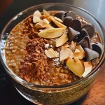 ['Close-up of creamy chocolate chia seed pudding topped with almond slices.', 'Side view of rich Keto chocolate chia pudding in a glass bowl with a spoon.', 'Juicy chocolate chia seed pudding garnished with coconut flakes and chocolate chips.', 'Delicious Keto chia seed pudding made with almond milk, displayed attractively.']