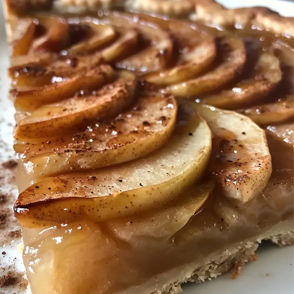 A close-up side view of a Maple Apple and Pear Tart, showcasing its golden crust and fruit filling.