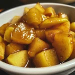['Close-up view of a bowl filled with pear compote, showcasing diced pears in a thick syrup.', 'A side view of a serving of pear compote, highlighting its glossy texture and rich color.', 'Detailed shot of pear compote with visible spices and ingredients, served in an elegant dish.', 'Close-up of luscious pear compote with a spoon, capturing the glistening fruit and sauce.']