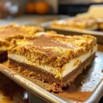 ['Side view of delectable pumpkin cheesecake bars with a crumbly gingersnap crust.', 'Close-up of creamy pumpkin cheesecake bars topped with a sprinkle of pumpkin pie spice.', 'Slice of pumpkin cheesecake bar showcasing a smooth filling and golden crust.', 'Rich pumpkin cheesecake bars displayed on a plate, highlighting their creamy texture.']