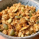 ['Close-up view of homemade Pumpkin Spice Protein Granola in a bowl.', 'Side angle of colorful Pumpkin Spice Protein Granola showcasing texture and ingredients.', 'Detailed shot of Pumpkin Spice Protein Granola with visible oats and pumpkin seeds.', 'Zoomed-in image of Pumpkin Spice Protein Granola highlighting its crunchy clusters.']