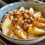 ['Close-up of a bowl filled with spiced pear oatmeal topped with chopped pears and nuts.', 'Side view of a creamy oatmeal dish featuring chunks of ripe pear and a sprinkle of spices.', 'Gourmet presentation of spiced pear oatmeal with a glossy finish, showing the texture and ingredients.', 'A vibrant bowl of oatmeal with pear pieces and cinnamon, styled for an enticing look.']