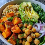 ['A vibrant close-up of a Sweet Potato Quinoa Bowl with colorful ingredients, viewed from the side.', 'A side view of a delicious Sweet Potato Quinoa Bowl showcasing sweet potatoes, quinoa, and fresh greens.', 'A close-up image highlighting a Sweet Potato Quinoa Bowl, featuring chickpeas, spinach, and almond sauce.', 'A detailed view of a Sweet Potato Quinoa Bowl filled with grains, vegetables, and a drizzle of almond sauce.']