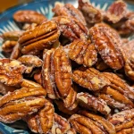 ['Close-up of toasting pecans in a skillet, showcasing their rich texture.', 'Side view of pecans being toasted, with a focus on their golden-brown color.', 'Juicy pecans in a frying pan, capturing the toasting process.', 'A detailed look at raw pecans heating up, emphasizing their transformation.']